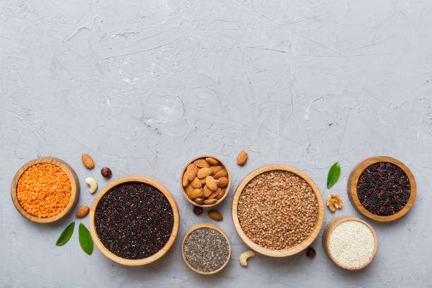 various superfoods in smal bowl on colored background. superfood as rice, chia, quinoa, lentils, nuts, sesame seeds, almonds. top view copy space - quinoa sesame chia flax seed foto e immagini stock