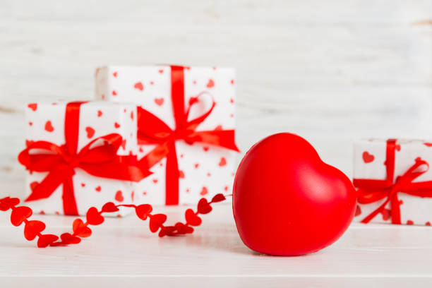 Two red heart shaped combination lock with chain floating in mid- air against blue sky.