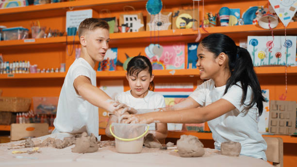 istock Handsome student dipping hand in to water to soften clay at class. Edification. 1961940571