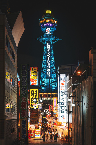 Osaka, Japan - December 7, 2023: Architectural landmark Tsutenkaku Tower illuminated at night in the Shinsekai district of Osaka, Japan.
