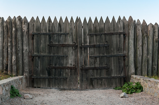 Old fortification stockade made of sharpened logs and wooden gates with forged hinges