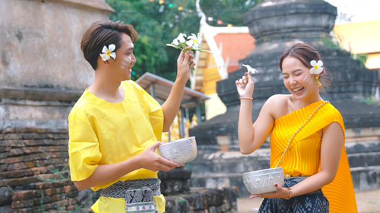 Couple dressed in traditional Thai clothing Playing in the water during Songkran Festival.