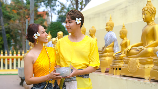 Young couple wears traditional Thai clothing during the Songkran festival, which is a ceremony for bathing Buddha images during the Thai Songkran festival.