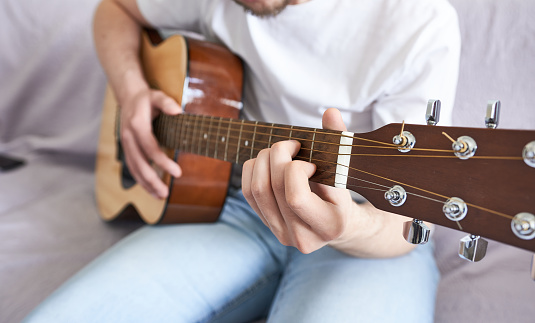 Man playing acoustic guitar at home, closeup. Musical instruments concept