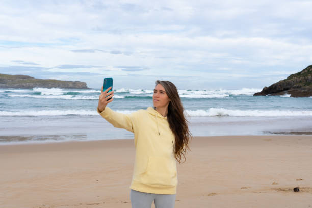 istock Woman taking a selfie with her cell phone on the beach 1961974520