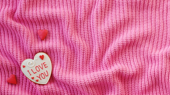 White Handmade Gingerbread with the Inscription I love you on a Pink Sweater Background. Love Declaration. Place for the text. Valentine Concept