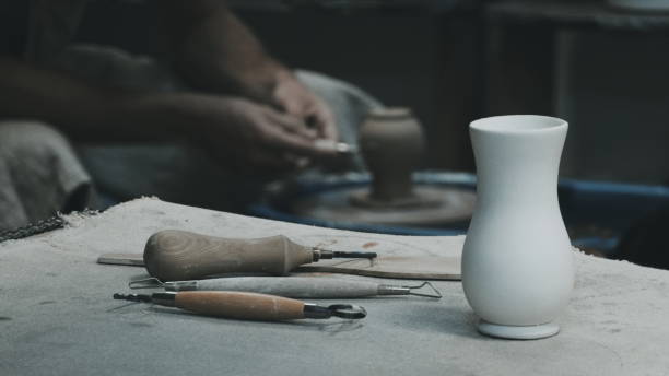 istock The sculptor at work. White Vase on Table. Potter's tools. Potter's hands on a Background. Filtered Photo 1962020740