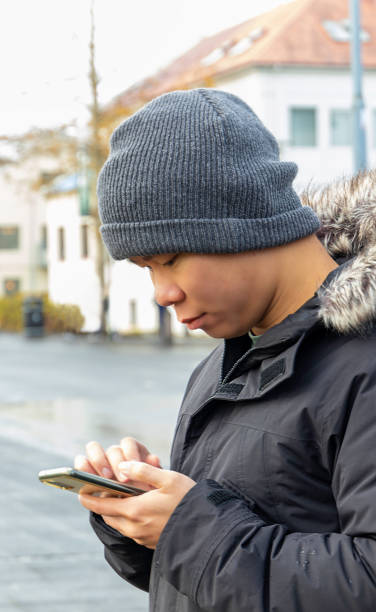 istock Young man in warm clothes checking smartphone 1962039644