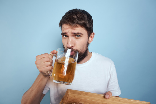 Cheerful man mug of beer fast food diet food lifestyle blue background alcohol. High quality photo
