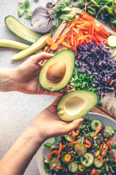 istock Avocado in female hands on a background of vegetables on the kitchen table. 1962059194