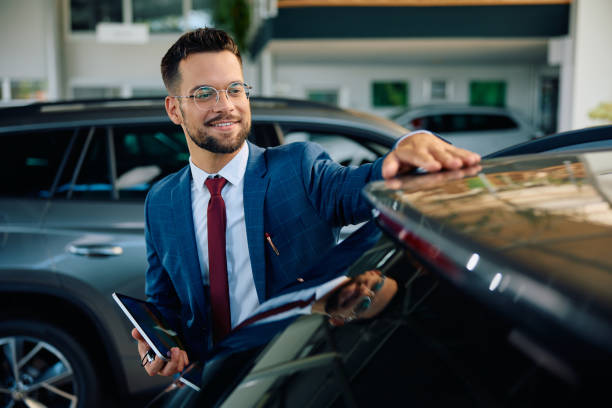 istock Happy car salesman working in a showroom. 1962059198