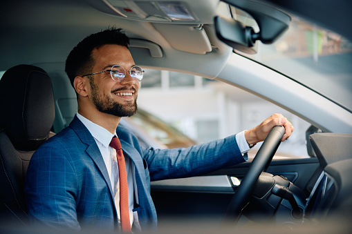 Happy businessman buying a new vehicle at car dealership.