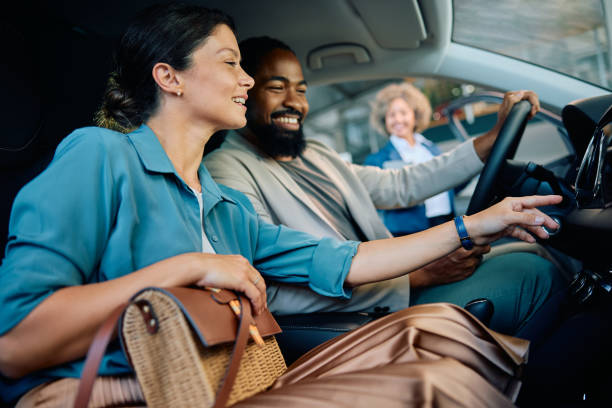 istock Happy multiracial couple testing their new car in a showroom. 1962065081