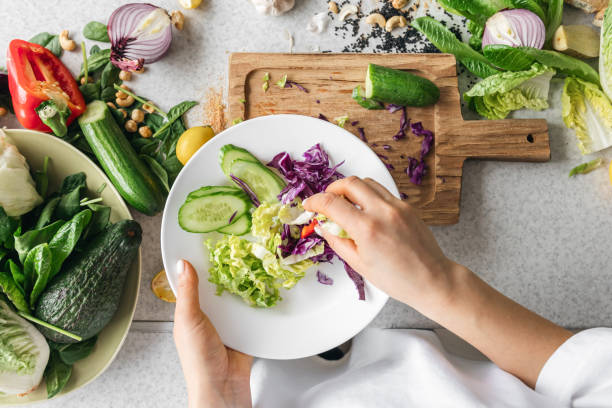 istock A plate with chopped fresh vegetables in female hands in the kitchen, top view. 1962068339