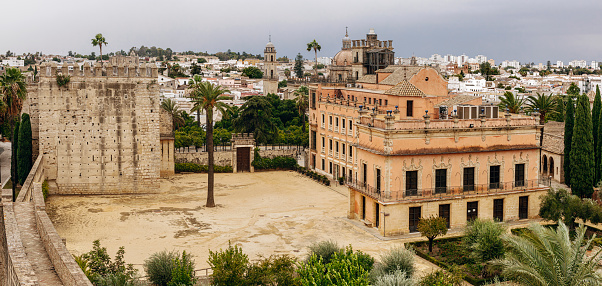The first fortress was probably built in the 11th-century, when Jerez was part of the small kingdom of the Taifa of Arcos de la Frontera, on a site settled since prehistoric times in the south-eastern corner of the city. The alcázar is one of a few structures that best exemplify Almohad architecture in the Iberian Peninsula.\n\nThe alcázar is made up of a grossly quadrangular line of walls, with a perimeter of approximately 4,000 m. The Octagonal Tower was constructed in the Almohad style, while the Palace of Villavicencio, which built in 1664, was done in Baroque style.
