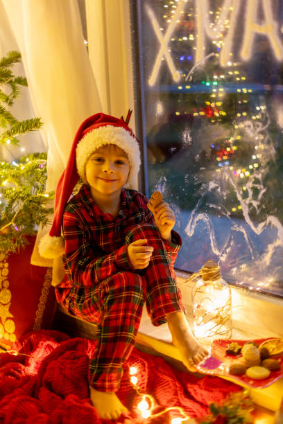 istock Cute child, sitting on a window, looking outdoors for Santa Claus 1962103337
