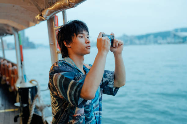 istock Young man taking a photo through mobile phone while standing on a boat 1962129909