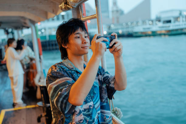 istock Young man taking a photo through mobile phone while standing on a boat 1962130500
