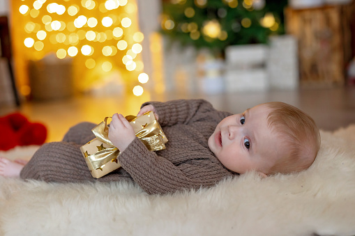 Cute newborn child, baby boy, with mom and dad on Christmas at home, enjoying first christmas holiday