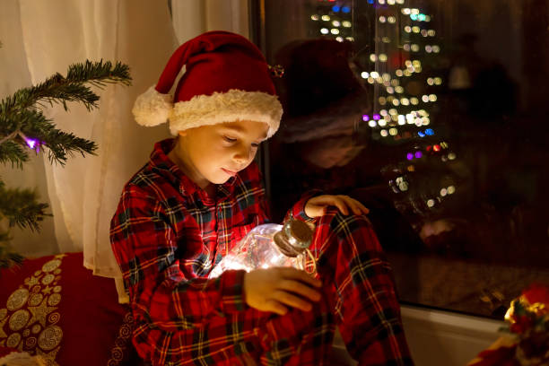 istock Cute child, sitting on a window, looking outdoors for Santa Claus 1962156911