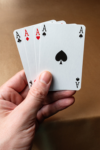 Four aces in the hand. Playing cards on the background of a golden table.