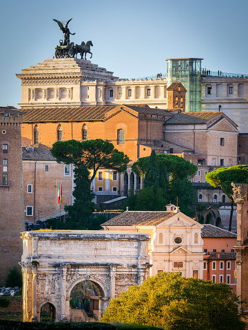 A delicate light illuminates a beautiful glimpse of the Roman Forum seen from the gardens of the Palatine Hill, in the heart of the Eternal City. On the horizon the Altare della Patria National Monument and the rear side of the Basilica di Santa Maria in Aracoeli, on the Capitoline Hill. Bottom center, the triumphal arch of Septimius Severus, along the Sacred Way, and the facade of the church of San Giuseppe at the Mamertine Prison, where the Holy Apostles Peter and Paul were locked up before their martyrdom. The Palatine Hill, one of the seven ancient hills of Rome, it is the place where important imperial palaces stood, such as the Domus Flavia and the Domus Augustana. In 1980 the historic center of Rome was declared a World Heritage Site by Unesco. Image in original 4:3 ratio and high definition quality.