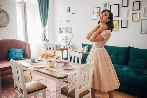 Classy young woman setting the table for her guests in her modern apartment.