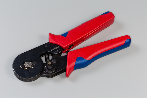 Hand crimping pliers for crimping of the round wire terminals on a gray background
