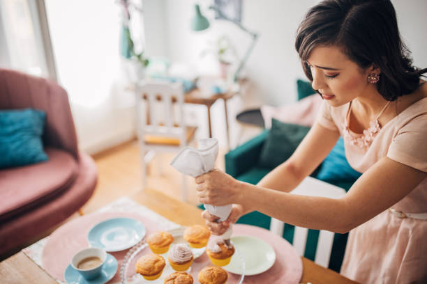istock Woman putting icing on muffins 1962174335