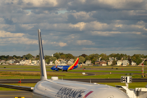 Logan International Airport, Boston Massachusetts, USA - October 2023.  Aircraft on the hard standing and the runway at the airport.