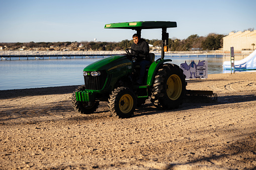 Granbury, United States – January 20, 2024: A man operating a tractor on a beach on a sunny day in Granbury, United States