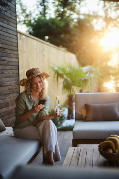 istock Happy woman text messaging on cell phone on a patio. 1962227472
