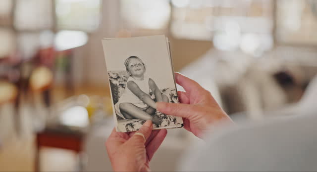 Memory, photo and zoom on hands of senior woman with nostalgia, past or history at home. Closeup, pictures and elderly female person remember with photograph collection in a house, lonely or alone