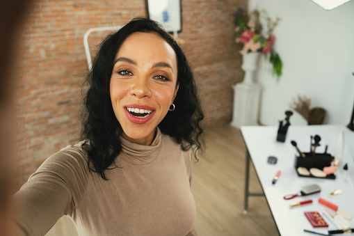 Woman influencer shoot live streaming vlog video review makeup crucial social media or blog. Happy young girl with cosmetics studio lighting for marketing recording session broadcasting online.