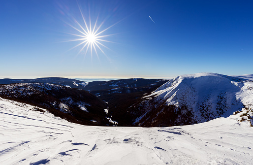 Winter mountains panorama with snow covered trees and blue sky with sun, the Giant mountains.