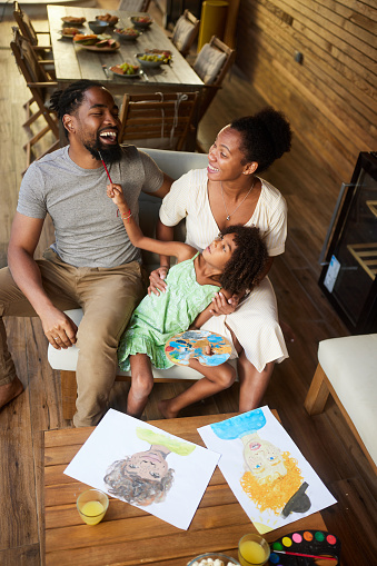 High angle view of happy African American family having fun while painting on a patio.
