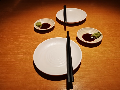 Focus scene on two pairs of empty plates and sauce wasabi in Japanese restaurant