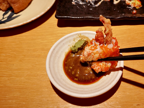 Focus scene on Japanese sushi dipping in wasabi sauce in restaurant