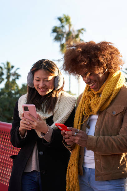 istock Multiracial young couple gathered outdoors using mobile phones cheerfully. 1962268631