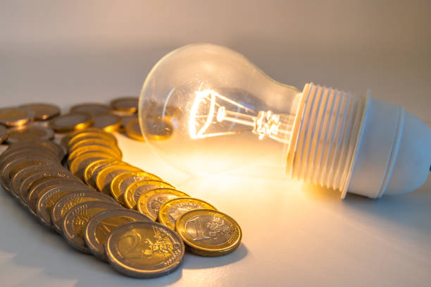 istock Light bulb lit, with coins around. Energy costs. 1962270234