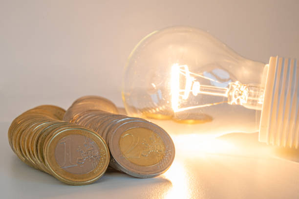 istock Light bulb lit, with coins around. Energy costs. 1962270263