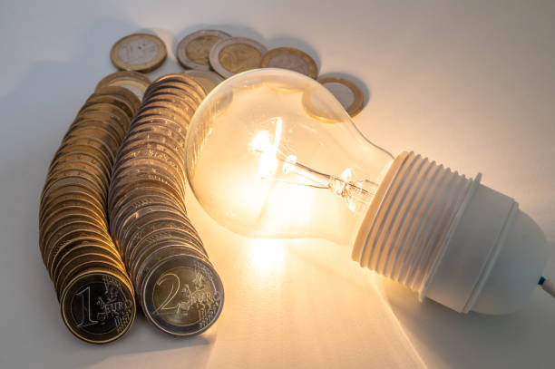 istock Light bulb lit, with coins around. Energy costs. 1962270819