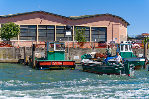 Old town of Italian City of Venice with cargo ship and dock at harbor on a sunny summer day. Photo taken August 7th, 2023, Venice, Italy.