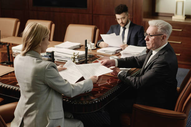 istock Biracial Group of Attorneys Working with Documents Sitting at Office Table 1962299786