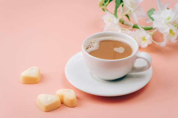 Coffee cup, heart shaped candies and white flowers on pink background. Valentines day concept. Closeup Coffee cup, heart shaped candies and white flowers on pink background. Valentines day concept. Closeup. cup shaped flower stock pictures, royalty-free photos & images