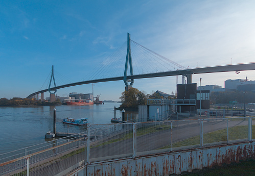Hamburg, Germany - 08/25/2023: Famous Köhlbrand Bridge at Port of Hamburg with red ship, tourist boat and blue sky