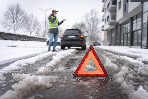 istock After vehicle breakdown, man talking on mobile phone, while warning triangle sign is on the road on winter cold weather 1962328408