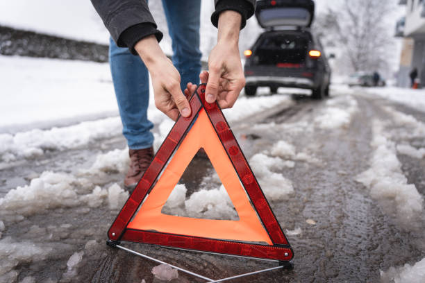 istock Unrecognizable man, put an warning triangle sign, during an vehicle breakdown on the road on winter cold weather 1962328922