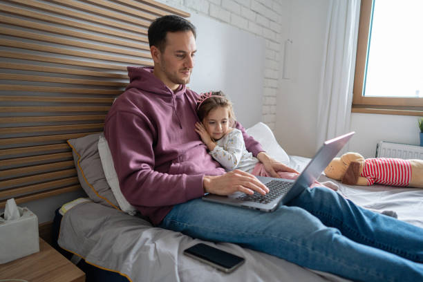 istock Father working on laptop while lying in the bed with his  daughter showing affection 1962342288