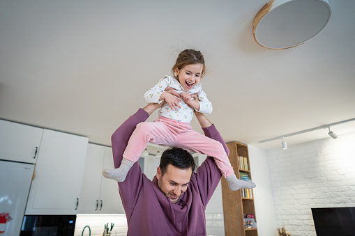 Young Caucasian man, an father playing with his daughter, at their modern home